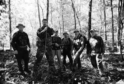 Daryl Colyer, Ken Helmer, Mark Porter, Jerry Hestand, Alton Higgins, and Paul Bowman stand at the foot of a mountain in Area X.